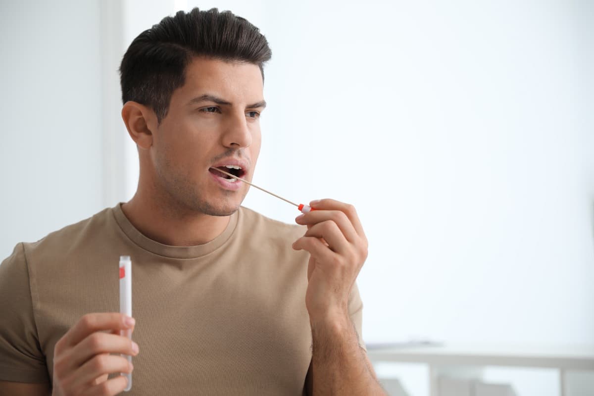Image of a man swabbing the inside of his cheek for DNA testing.