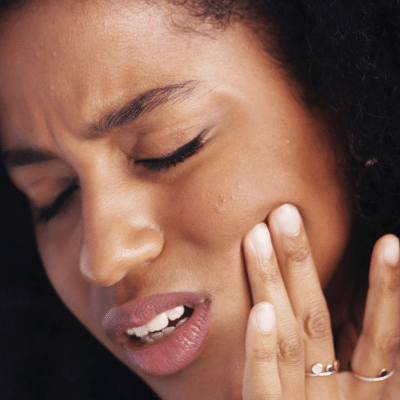 Woman holding her jaw in pain, representing tmj treatment in chesapeake va