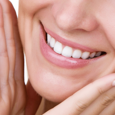Closeup of a woman smiling while holding her hands up to her face, showcasing her white smile, representing smile makeover in chesapeake va