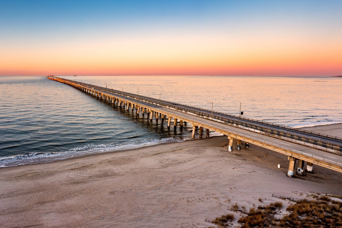 Chesapeake bay bridge-tunnel at sunrise with soft pastel sky over calm waters in virginia.