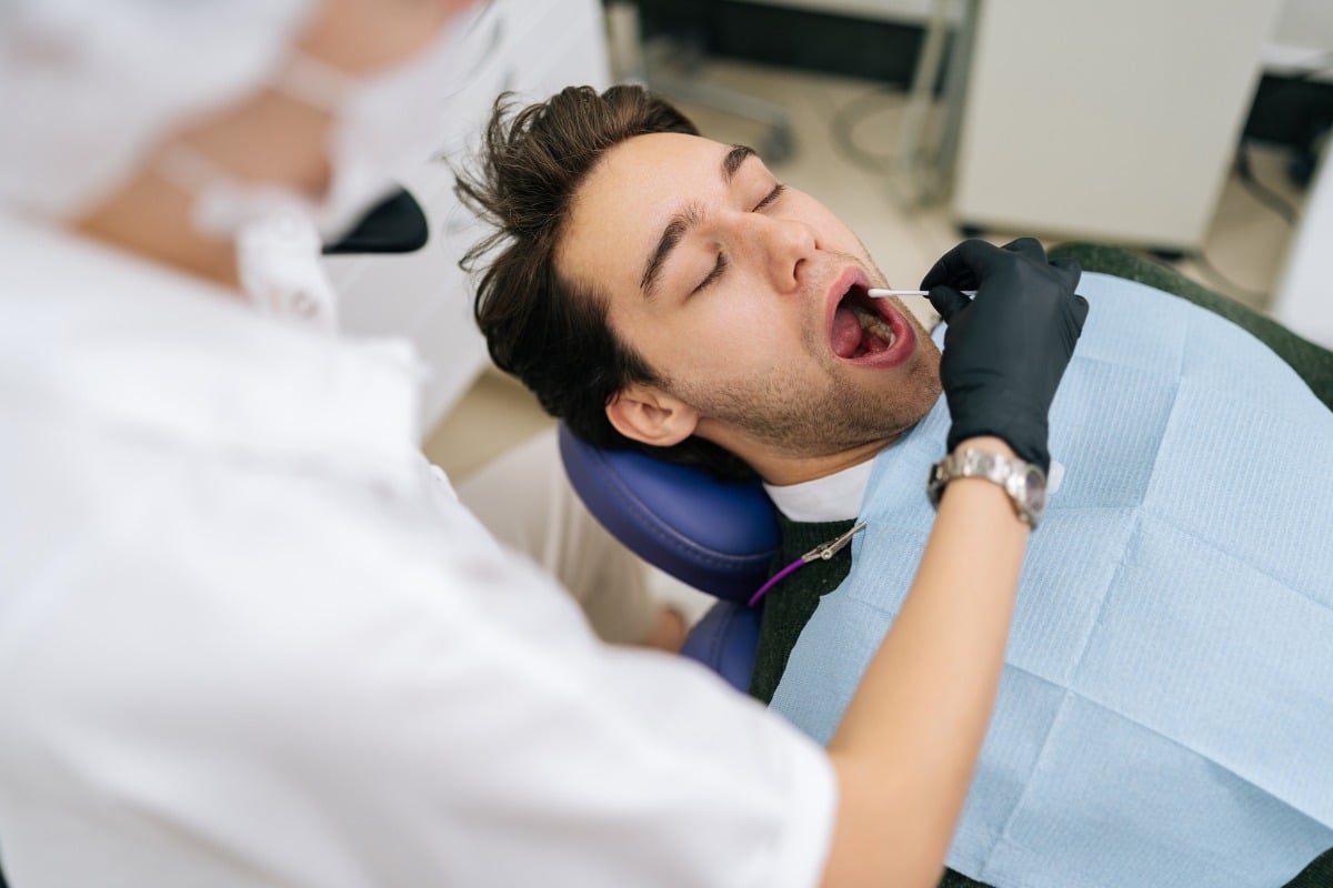 Dentist performing an oral brush biopsy on a patient using OralCDx for early detection of oral cancer.