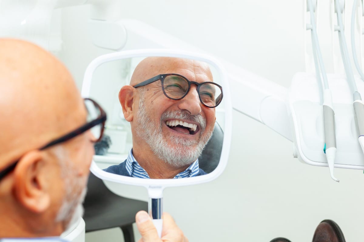 Smiling man looking in the mirror after receiving Nobel Biocare dental implants.