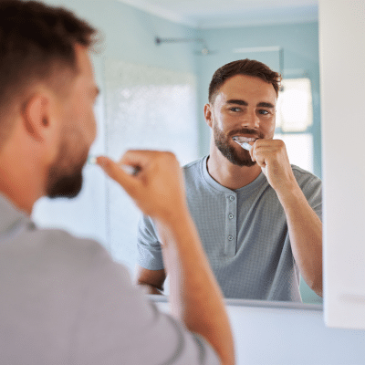 Man brushing his teeth, representing maintaining cosmetic dental work