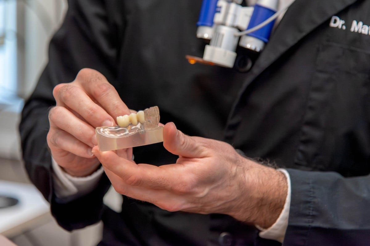 Expert dentist in chesapeake, virginia holding a dental bridge model for restorative treatment planning.